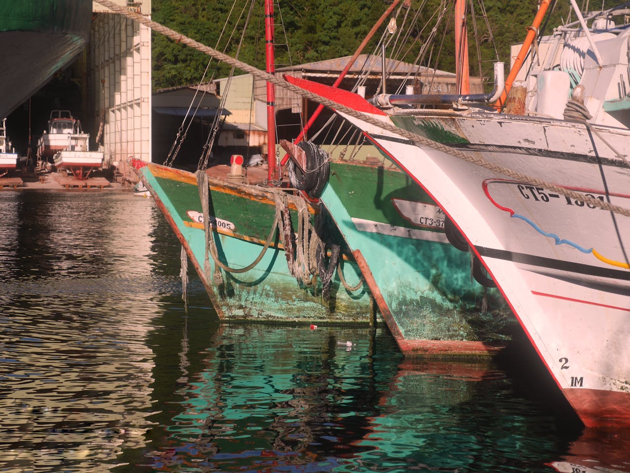 Vibrant boats at dock reflecting on calm water, creating a serene scene.